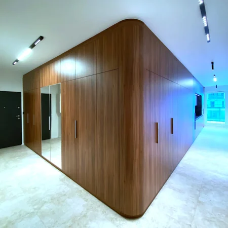 Full-height walnut veneer wardrobe with rounded corners and continuous wood grain in modern interior
