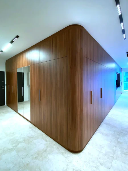 Full-height walnut veneer wardrobe with rounded corners and continuous wood grain in modern interior